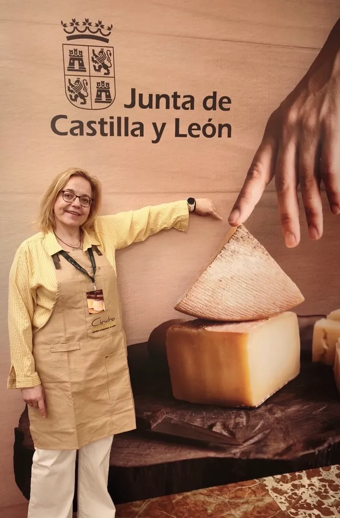 Ruth Lozano en el estand de la Junta de Castilla y León durante el concurso Cincho, señalando una gran cuña de queso.